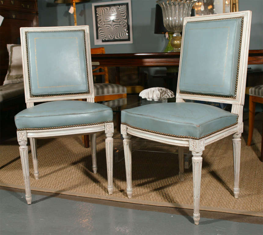 A pair of Louis XVI style side chairs painted and upholstered in a soft blue tooled leather with nail heads.  Classic, yet chic, these chairs are timeless.